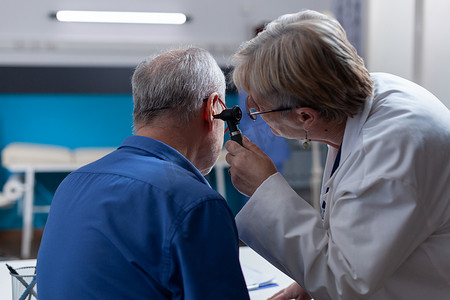医生在检查时手持耳镜为患者进行耳部咨询