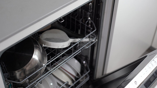 厨房洗碗机摄影照片_打开洗碗机，里面有干净的餐具。