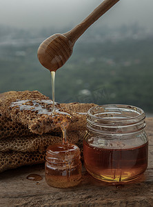 美味的蜂蜜从木制蜂蜜北斗滴下，粘在新鲜的蜂窝上。