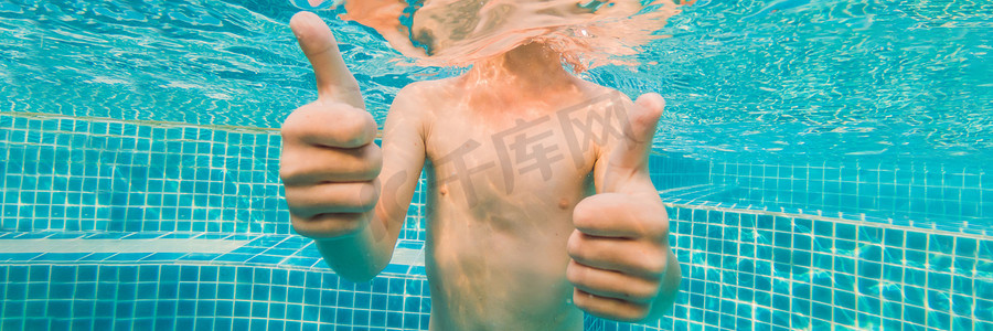 水下小男孩戴着护目镜在游泳池里玩耍。