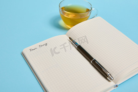打开记事本，上面写着“亲爱的日记”，蓝色背景的茶杯旁边有一支墨水笔，有复制空间