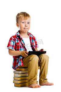 坐在书本上的男孩摄影照片_男孩拿着平板电脑坐在书本上