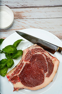 带骨牛排或丁骨牛排或上等腰肉牛排生放在木桌上的白盘子上。