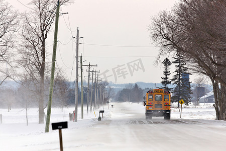 冬天，校车沿着飘雪和吹雪的乡村道路行驶