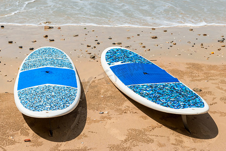 一对冲浪板位于海边的沙滩上