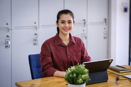 在销售增长增加后，一位美丽的女人微笑着高兴地在平板电脑屏幕上使用销售利润计算器。
