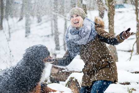 冬天遛狗的女人，两人都在雪地里探索