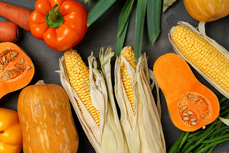 南瓜摄影照片_深色背景下的各种成熟蔬菜，包括南瓜和玉米