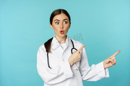 惊讶的医务人员的肖像，女医生用手指指着右边，说哇很惊讶，反应很感兴趣，站在绿松石背景上