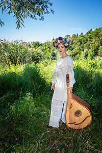 夏日阳光明媚的日子里，身着白色民族服饰的乌克兰美女站在班杜拉身边