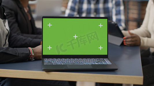 办公桌上有绿色屏幕背景的笔记本电脑显示屏