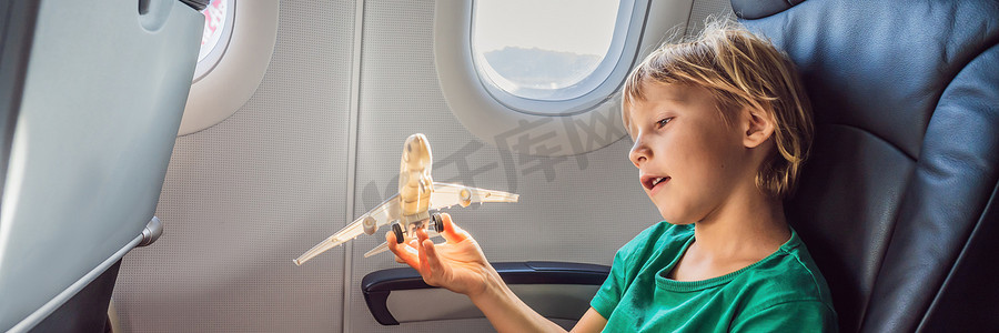 小男孩在度假横幅上飞行的商用喷气式飞机上玩玩具飞机，长格式