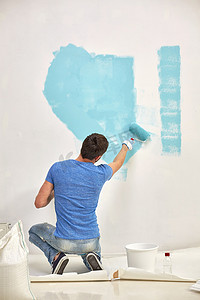 家里有蓝色滚轴油漆墙的男人