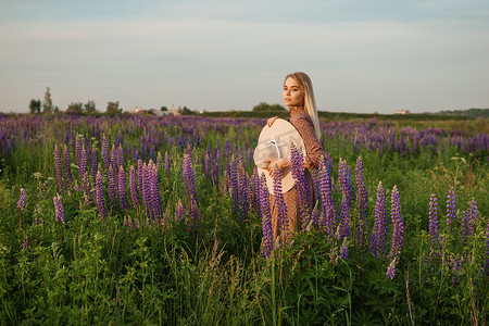 一位戴着草帽的美丽女子走在开满紫色花朵的田野里。