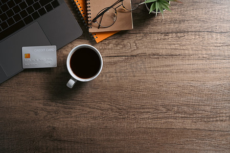 顶视图笔记本电脑、信用卡、咖啡杯和木桌上的笔记本。