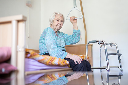 病床上摄影照片_96 岁的老年妇女坐在临终关怀医院的病床上。