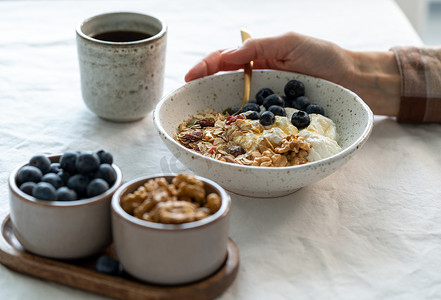 酸奶燕麦摄影照片_在白桌上的碗里吃健康的生活方式早餐，包括麦片麦片和酸奶