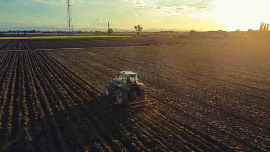 砥砺深耕摄影照片_意大利皮亚琴察 — 9 月 22 日，农民在日落时驾驶拖拉机深耕土地