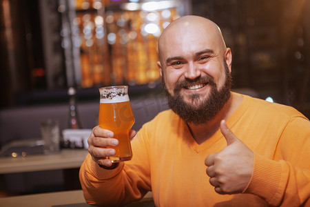 干杯聚会摄影照片_留胡子的男人在酒吧享受喝啤酒