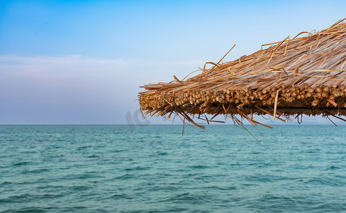 太阳伞摄影照片_傍晚大海背景下的太阳伞边缘