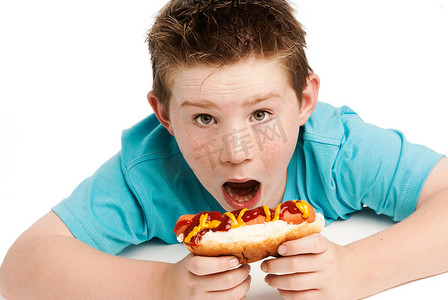 饥饿的小男孩吃热狗。