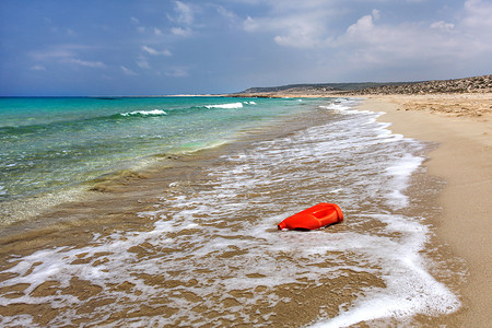 美丽的未受污染的海滩上亮红色塑料油（或洗涤液）容器。
