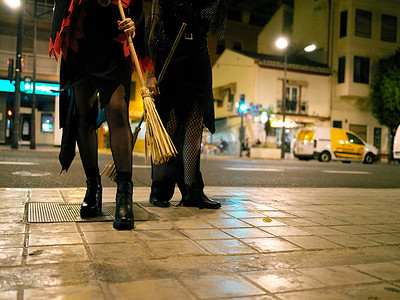 西班牙巴伦西亚街头，两名年轻女子万圣节装扮成女巫的双腿。