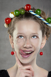 一个头上戴着糖果花环的滑稽少女露出了她的舌头。