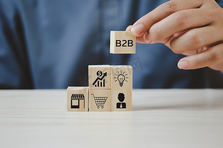 手工将带有 B2B 企业对企业图标和符号的木制立方体放在桌子和复制空间上。商业概念。
