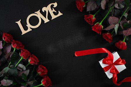 黑色背景上带有木字“爱”的红玫瑰花