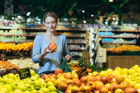 一位女士在超市里，一位买家在挑选苹果水果，