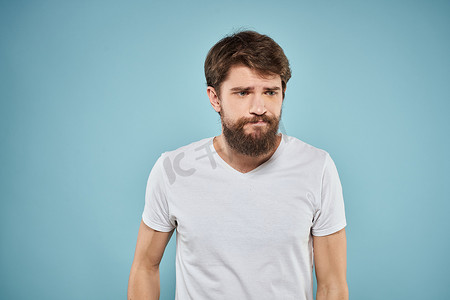表情摄影照片_穿白色T恤的男人情绪面部表情裁剪视图工作室蓝色背景生活方式