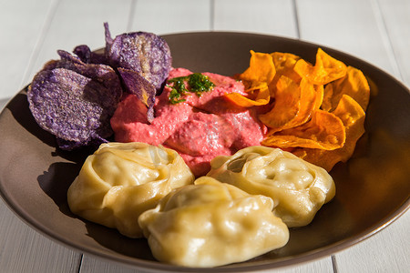 蒸肉饺子曼蒂配甜菜鹰嘴豆泥和彩色紫丁香薯片和红薯片