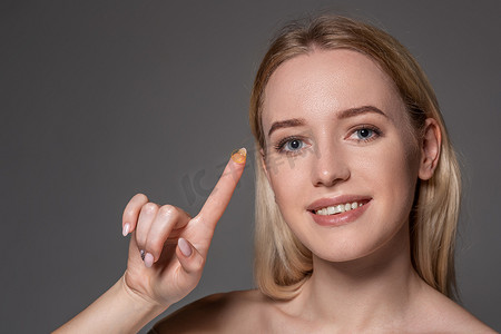 年轻女子在食指上拿着隐形眼镜，有复制空间。