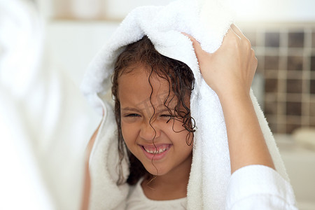 母亲为她在家快乐、无忧无虑、微笑的女儿进行日常护发、清洁和洗头。