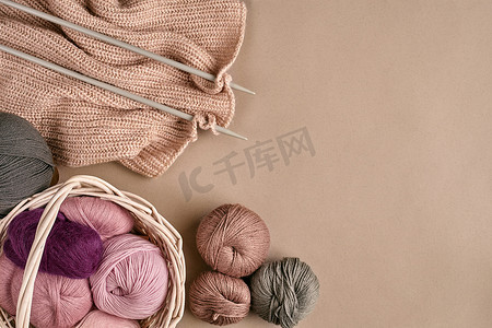 美利奴羊毛纱线球，在米色表面上用织针编织。