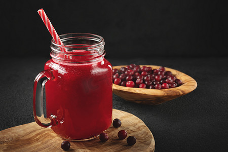 红杯摄影照片_在玻璃罐杯中用吸管在黑桌上治愈蔓越莓汁。