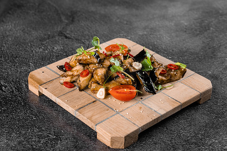 木板上的炸茄子，灰色背景上装饰着辣椒、大蒜、香菜、芝麻。