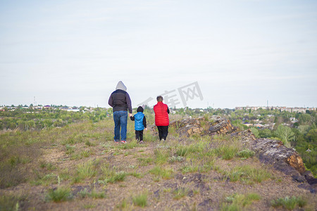 发生的摄影照片_一个男人和孩子们站在一块岩石上，看着下面发生的事情。