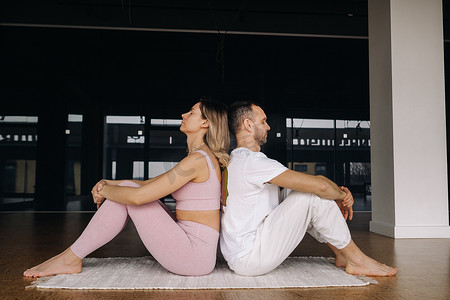 双人瑜伽摄影照片_一名女子和一名男子正在健身房里进行双人体操瑜伽