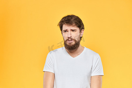表情摄影照片_留着胡须的男人的情绪手势，双手面部表情白色T恤黄色背景