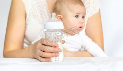 可爱的奶瓶摄影照片_母亲用奶瓶喂养婴儿。