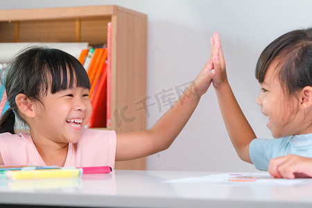 打招呼摄影照片_小女孩向坐在教室里的朋友们打招呼。