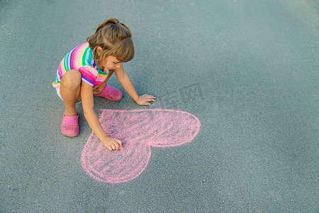 儿童用粉笔在沥青上画画。