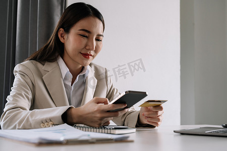 订购弹窗摄影照片_亚洲女性手持信用卡和智能手机，年轻女性在线支付，使用银行服务，输入信息，购物，在网上商店订购，进行安全支付