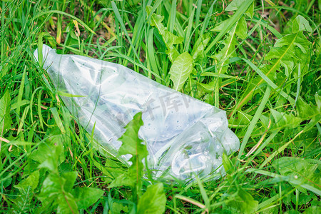 躺在绿草中的皱巴巴的塑料瓶