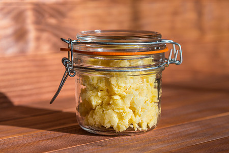 阳光明媚的厨房里，木桌上的透明罐子里放着大蒜奶酪酱。