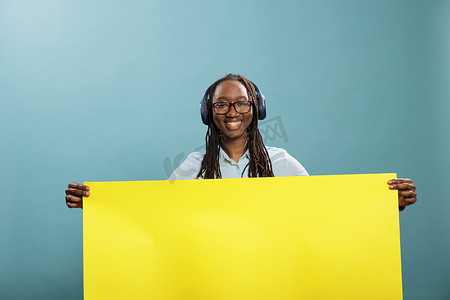 开朗快乐微笑自信的女人拿着黄色空白纸横幅板用于广告投放。