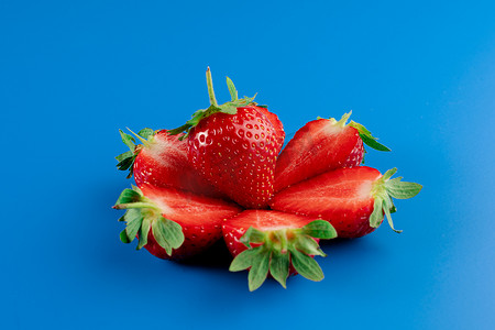 绿色块背景摄影照片_草莓切片特写和蓝色背景上的整块草莓。