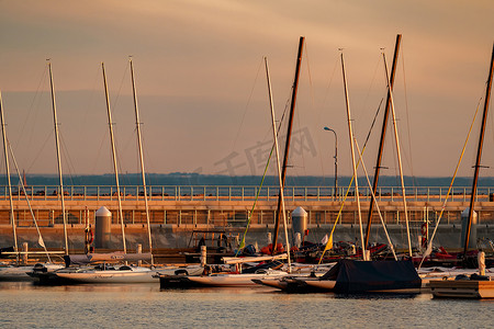 俄罗斯，圣彼得堡，2021年6月10日：日落时分，几艘帆船停在俄罗斯天然气工业股份公司摩天大楼附近的一个新港口，还有浮桥和码头，背景是老式木制护卫舰